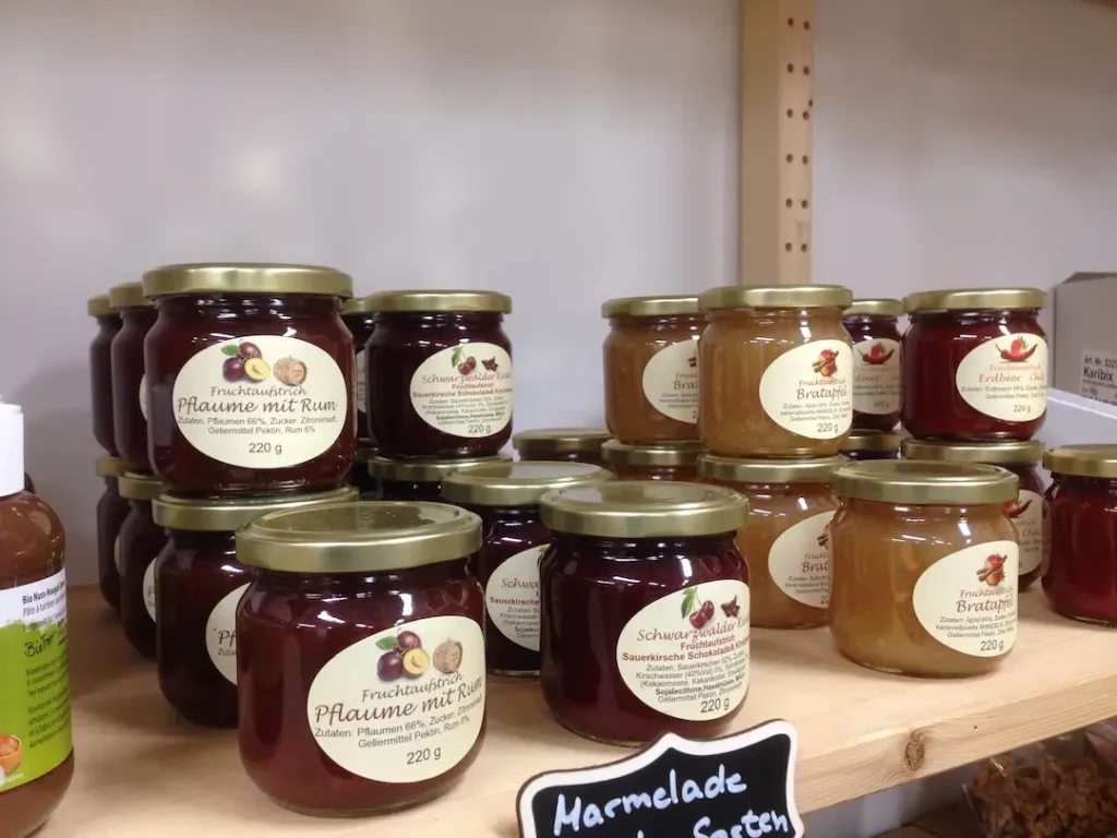 Gläser mit hausgemachten Fruchtaufstrichen der Sorten Pflaume mit Rum und Bratapfel im Verkaufsregal des Hofladens.