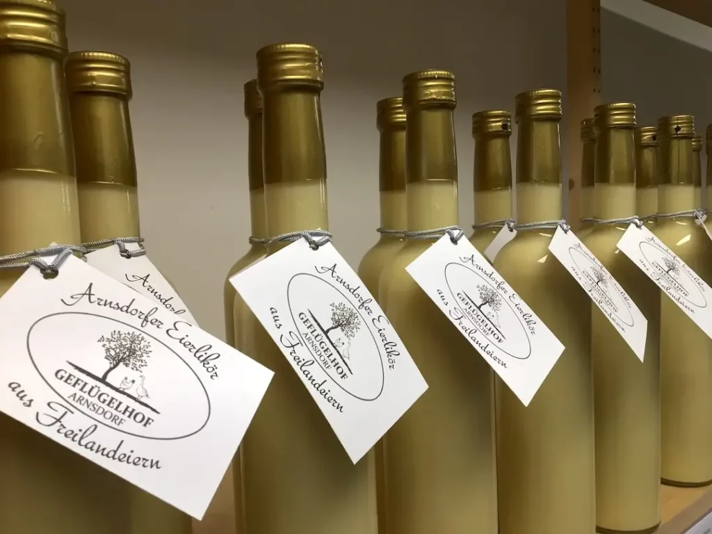 Mehrere Flaschen goldgelber, hausgemachter Eierlikör mit dem traditionellen Etikett vom Geflügelhof Arnsdorf aus Freilandeiern.