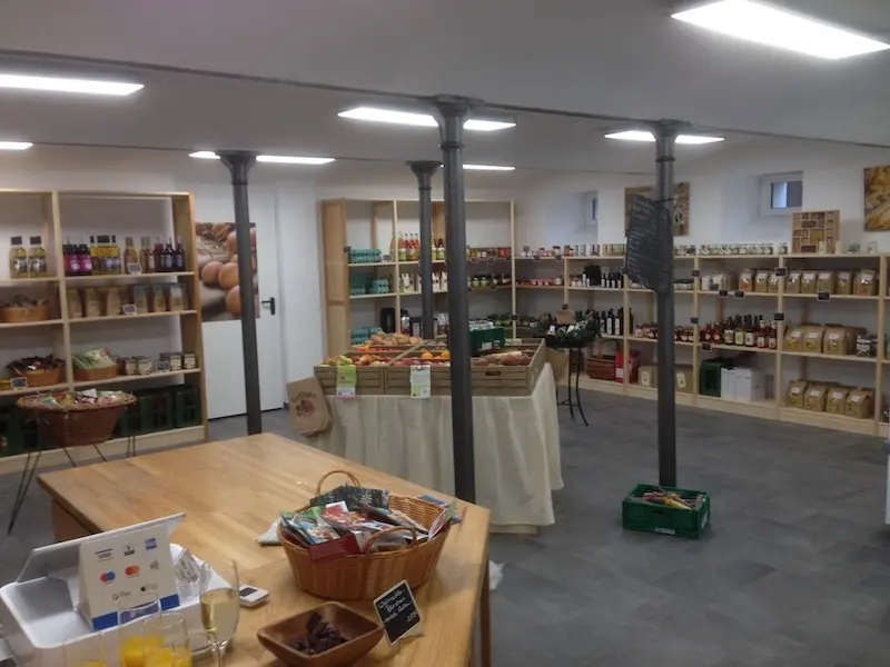 Regale mit verschiedenen Produkten im Hofladen Penig bei Arnsdorf, darunter Brotkörbe, Flaschen und Verpackungen.