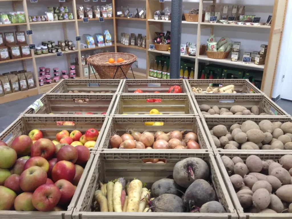 Mehrere Verkaufskisten voller Äpfel, Zwiebeln, Kartoffeln und Roter Bete auf dem zentralen Markttisch im Hofladen Arnsdorf.